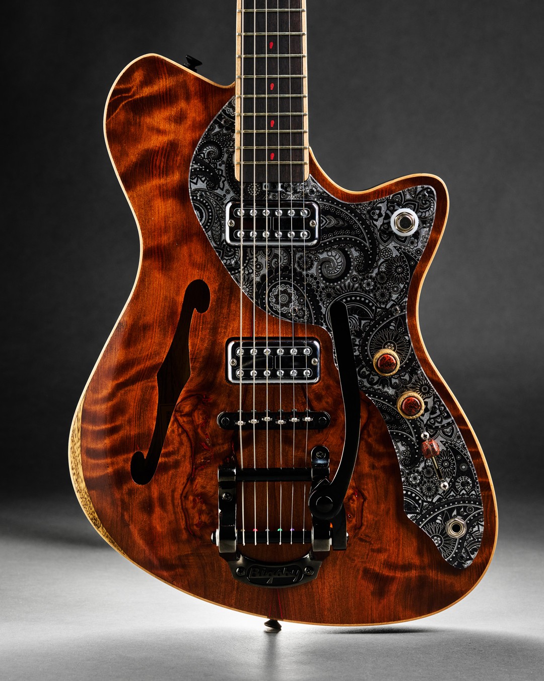 Wood-grain electric guitar with an ornate pickguard